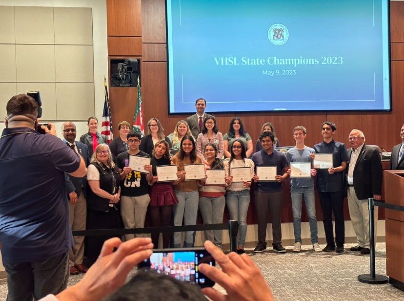 Woodgrove Senior Elizabeth Brubaker, accompanied by other Loudoun County school student representatives, speak at a LCPS school board meeting on May 9th, 2023. The front row of students are being recognized for their championship in the Virginia High School League. Photo provided by Elizabeth Brubaker.
